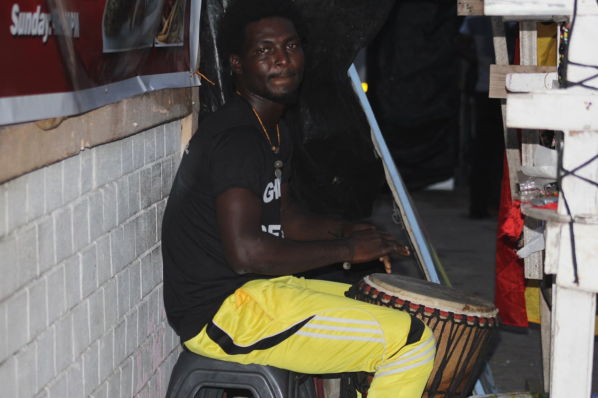 A man playing a djembe drum, representing oral and musical storytelling tradition